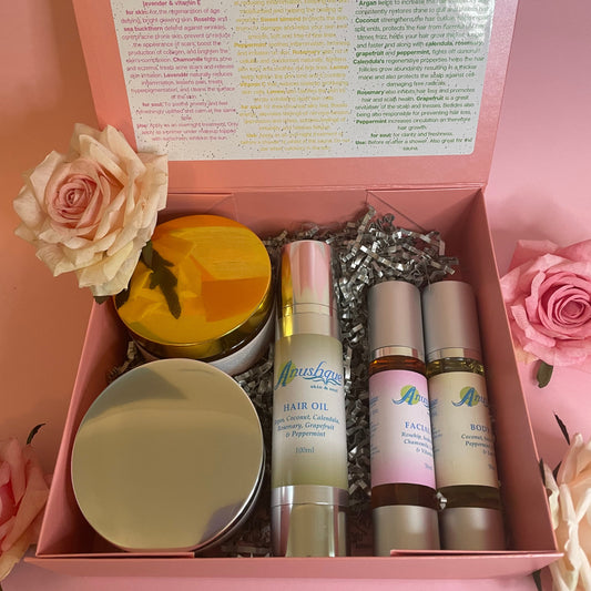 Gift box containing two jars of body butter, one bottle of hair oil, one bottle of facial oil, and one bottle of body oil